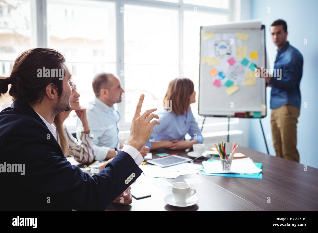 Altoparlante chiamando un collega con la mano alzata durante la riunione Foto Stock