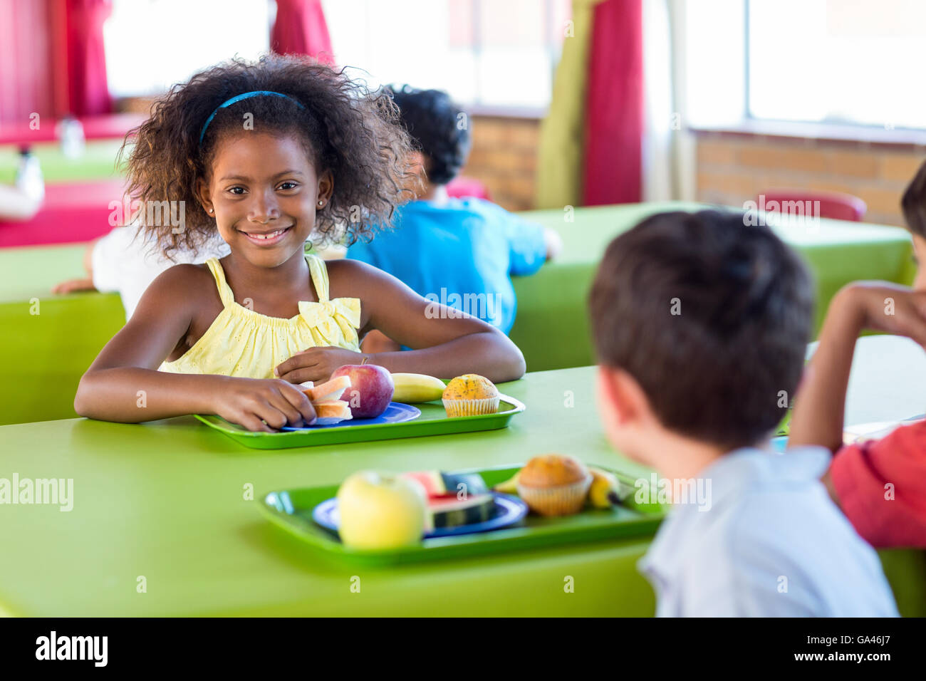 Ragazza sorridente con i compagni di classe avendo pranzo Foto Stock