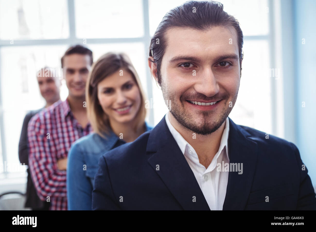 Imprenditore sorridente con i colleghi in piedi in fila Foto Stock