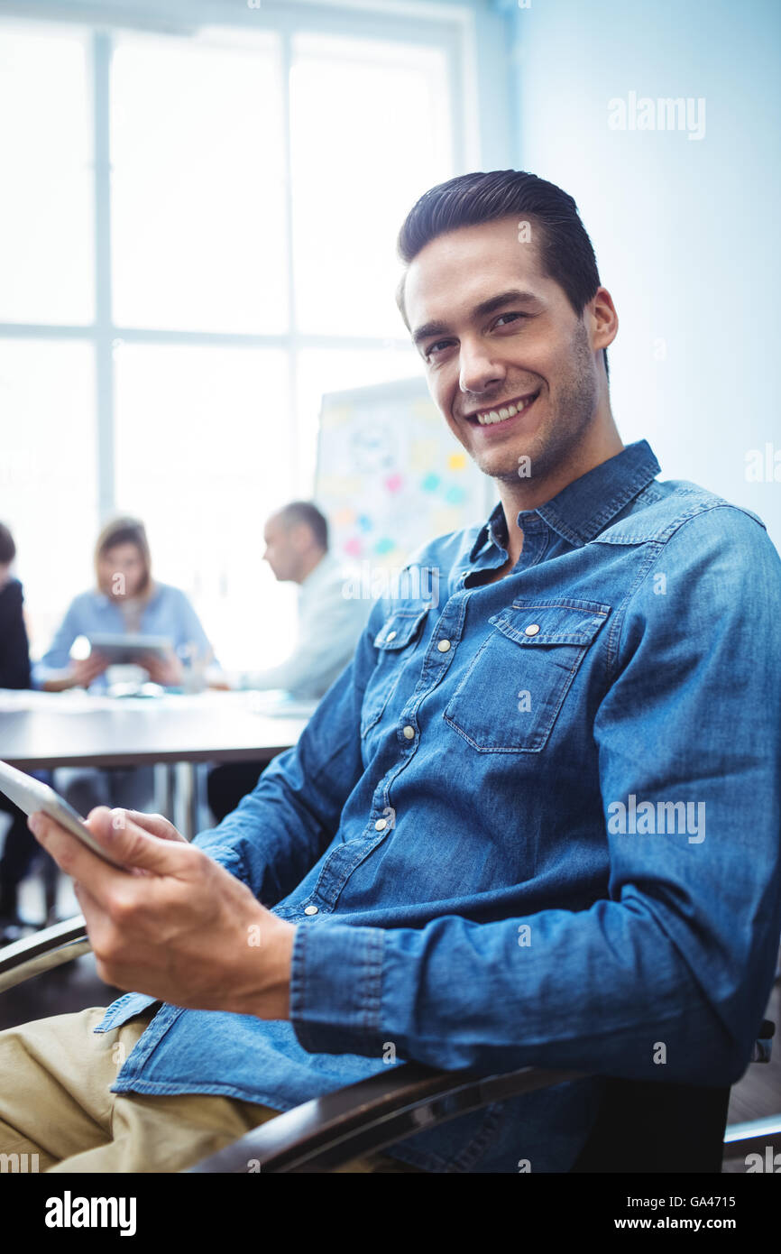 Happy businessman utilizzando digitale compressa contro i colleghi nella sala riunioni Foto Stock