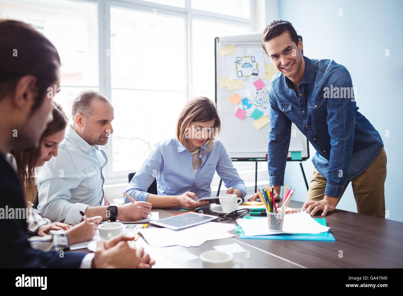Imprenditore sorridente con i colleghi di lavoro nella sala riunioni Foto Stock
