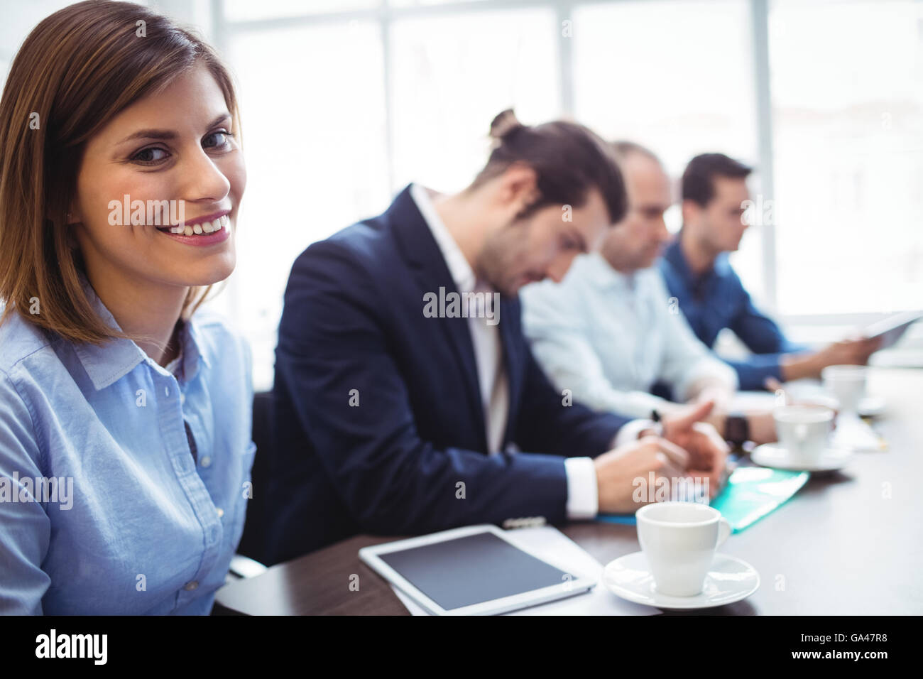 Imprenditrice sorridente con i colleghi di lavoro nella sala riunioni Foto Stock