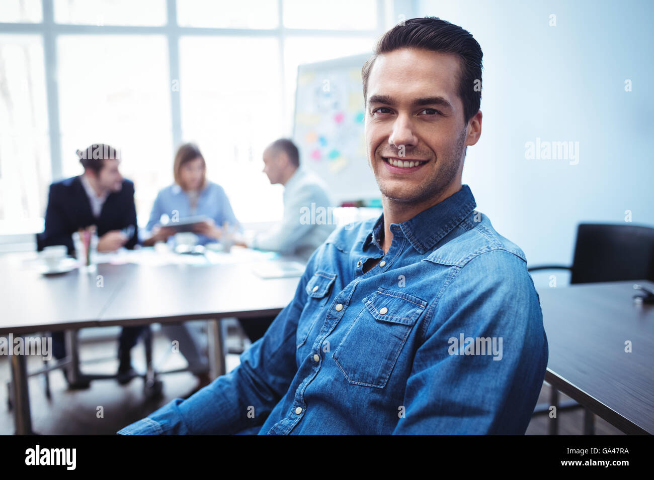 Imprenditore seduto contro i colleghi nella sala riunioni Foto Stock
