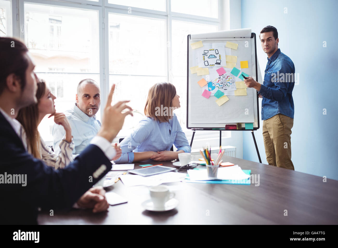 Altoparlante chiamando un collega con la mano alzata durante la riunione Foto Stock