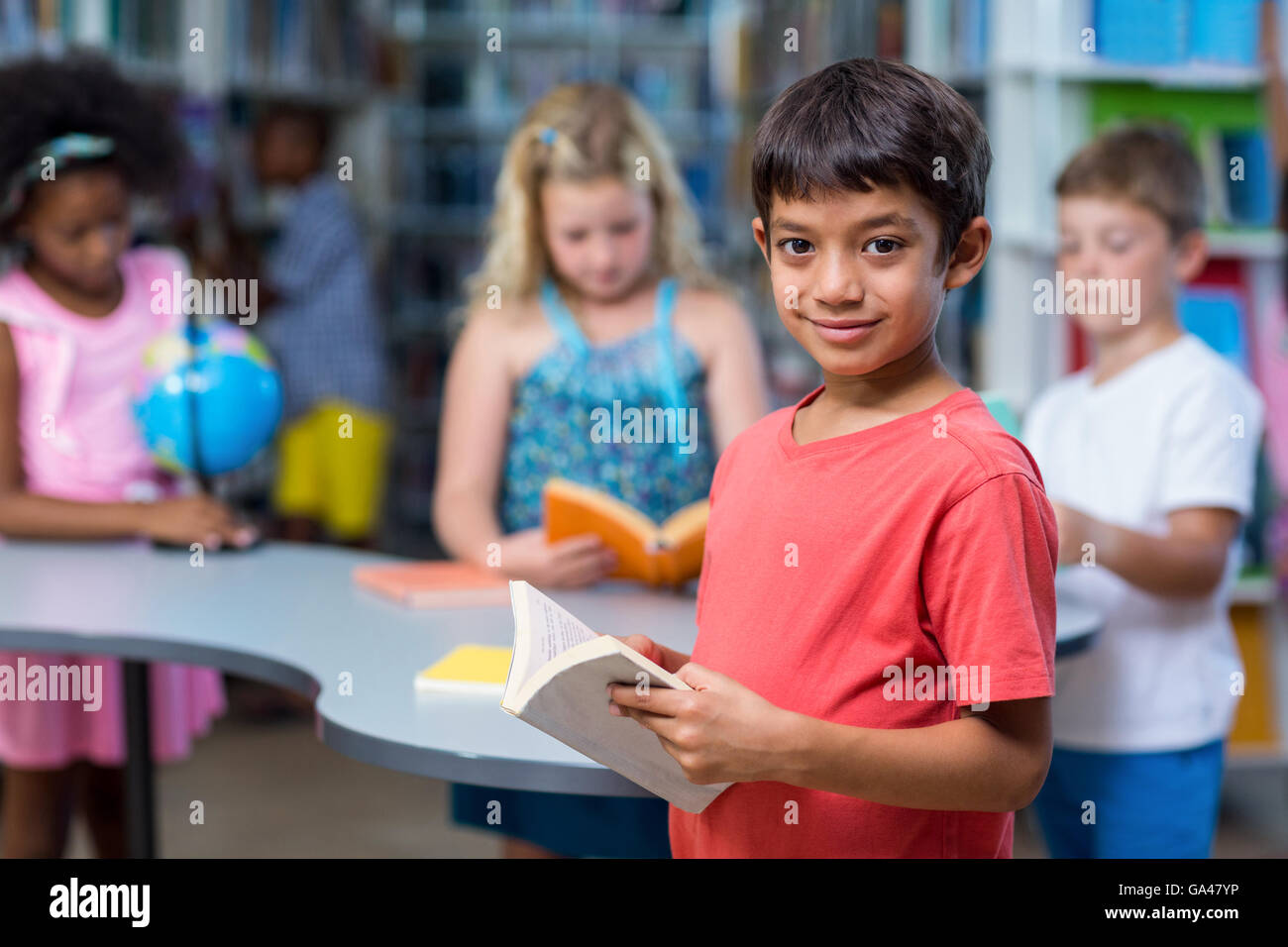 Ragazzo sorridente azienda libri contro i compagni di scuola Foto Stock