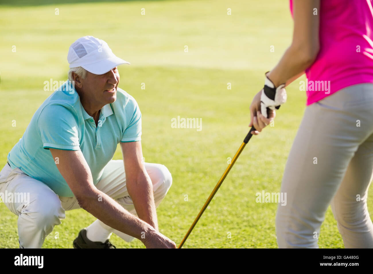 Coppia golfista uomo accovacciato mentre l'insegnamento donna Foto Stock