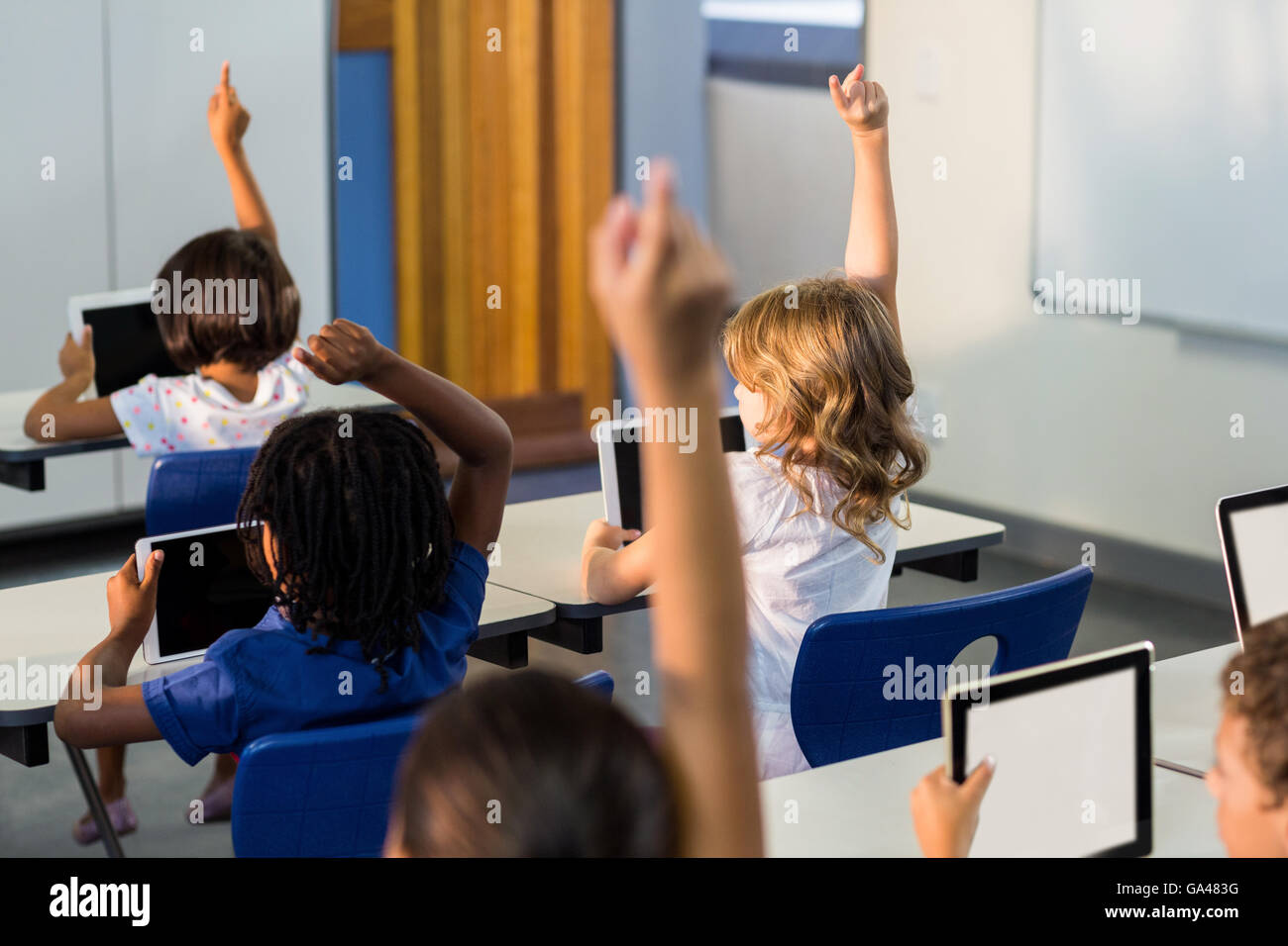 I bambini con le compresse di digitale ad alzare la mano Foto Stock