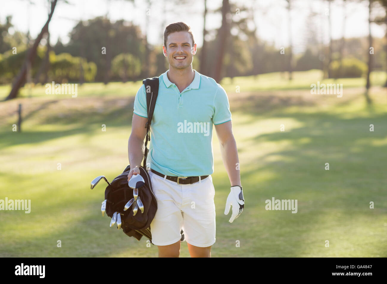 Ritratto di giovane sorridente uomo che porta borsa da golf Foto Stock