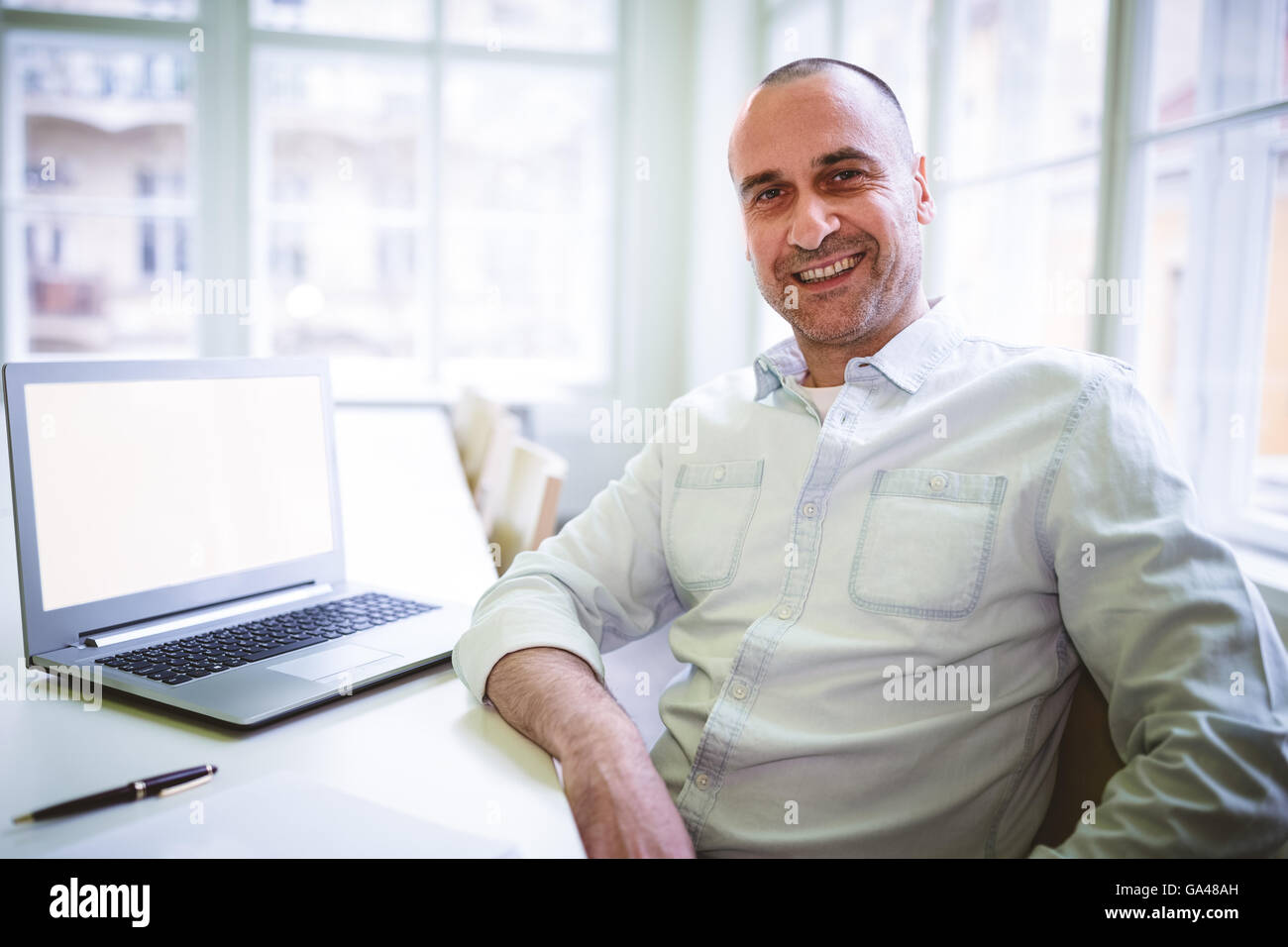 Imprenditore sorridente seduta dal computer portatile Foto Stock