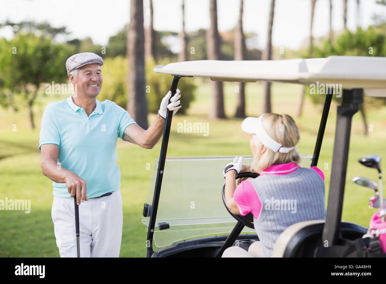 Uomo maturo guardando donna seduta in golf buggy Foto Stock
