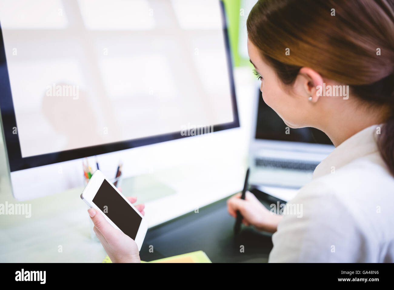 Graphic designer tenendo il telefono mentre si lavora alla scrivania Foto Stock