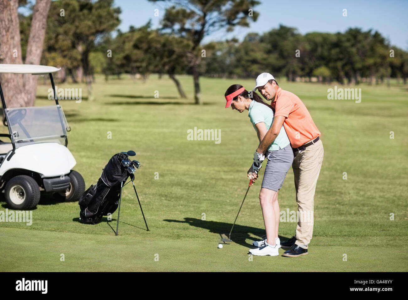Vista laterale dell'uomo donna di insegnamento per giocare a golf Foto Stock