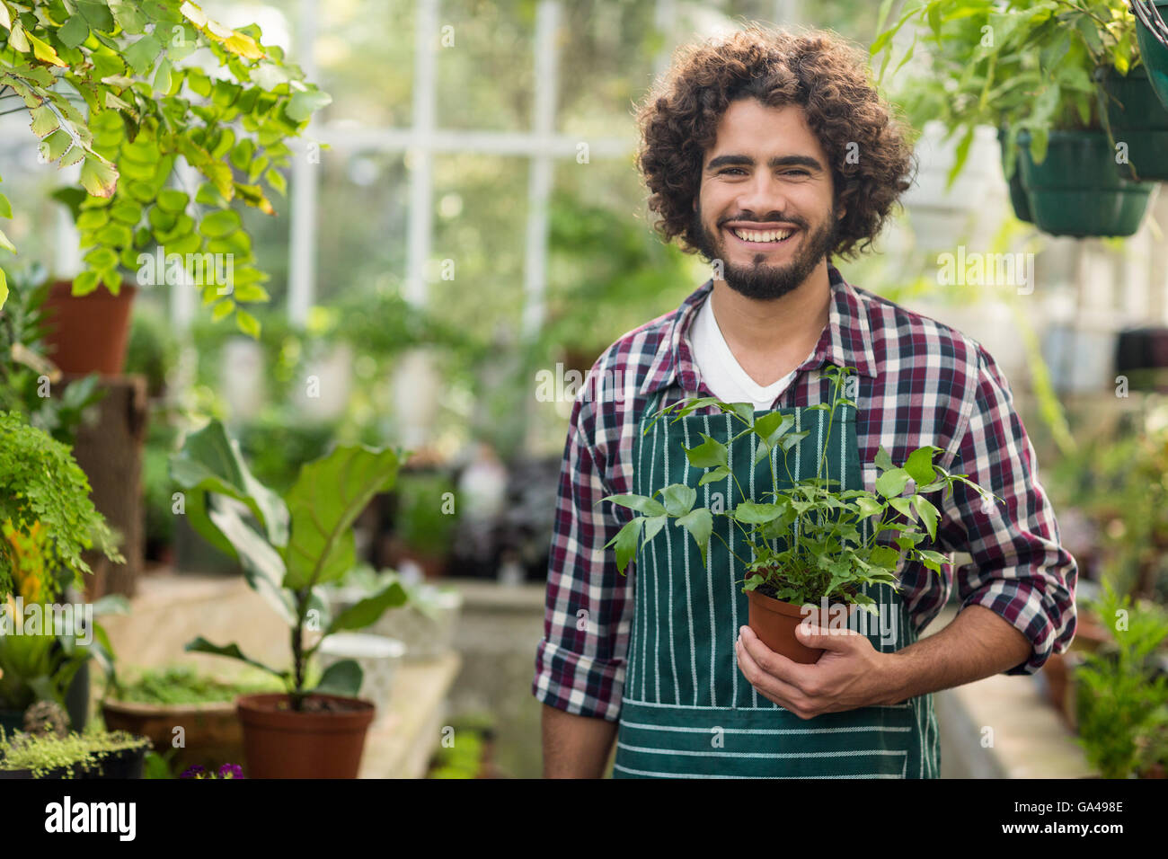 Sorridente giardiniere maschio azienda pianta in vaso Foto Stock