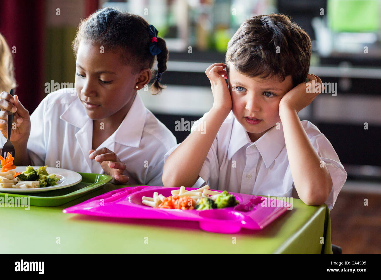 Ragazzo premuroso con i compagni di classe in mensa Foto Stock