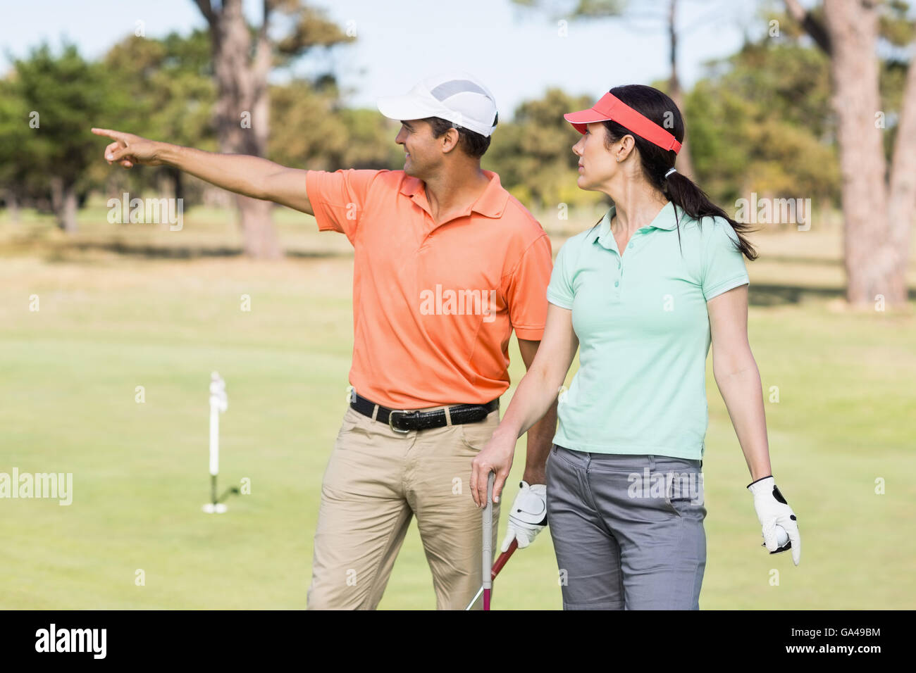 Sorridente golfista uomo rivolta mentre in piedi da donna Foto Stock