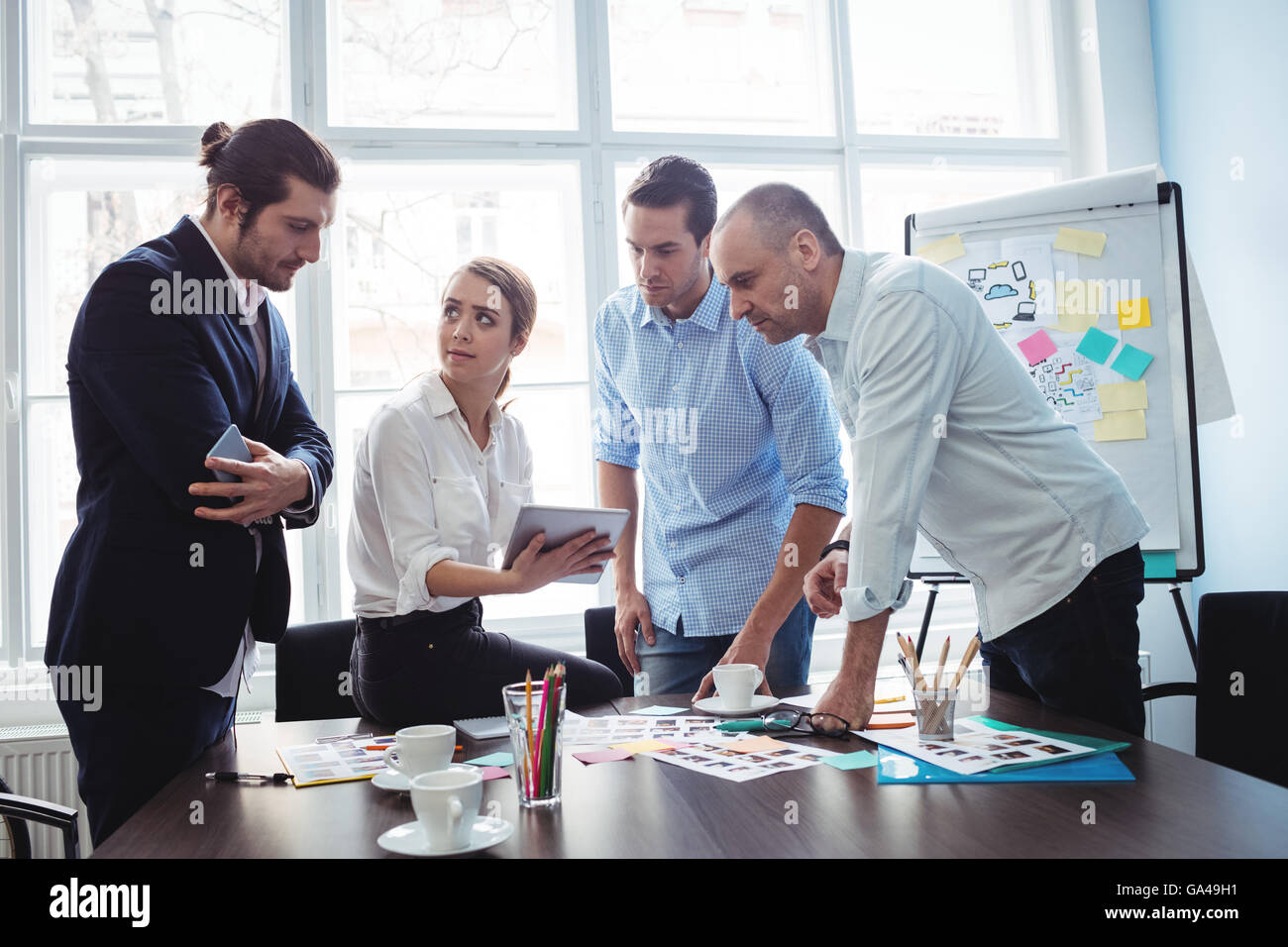 Redattori con documenti e tavoletta digitale discutendo in sala riunioni Foto Stock
