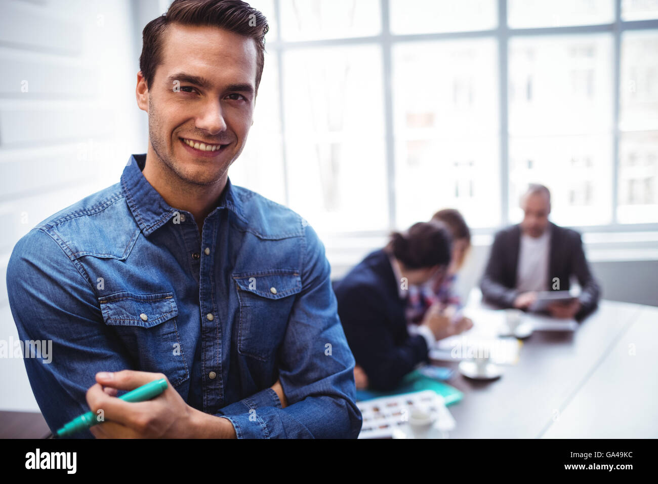Ritratto di happy businessman contro come i colleghi in sala riunioni Foto Stock