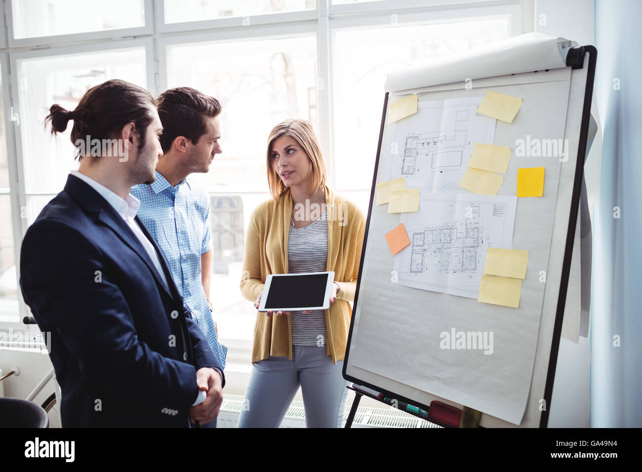 Imprenditrice che mostra digitale compressa ai colleghi durante la riunione Foto Stock