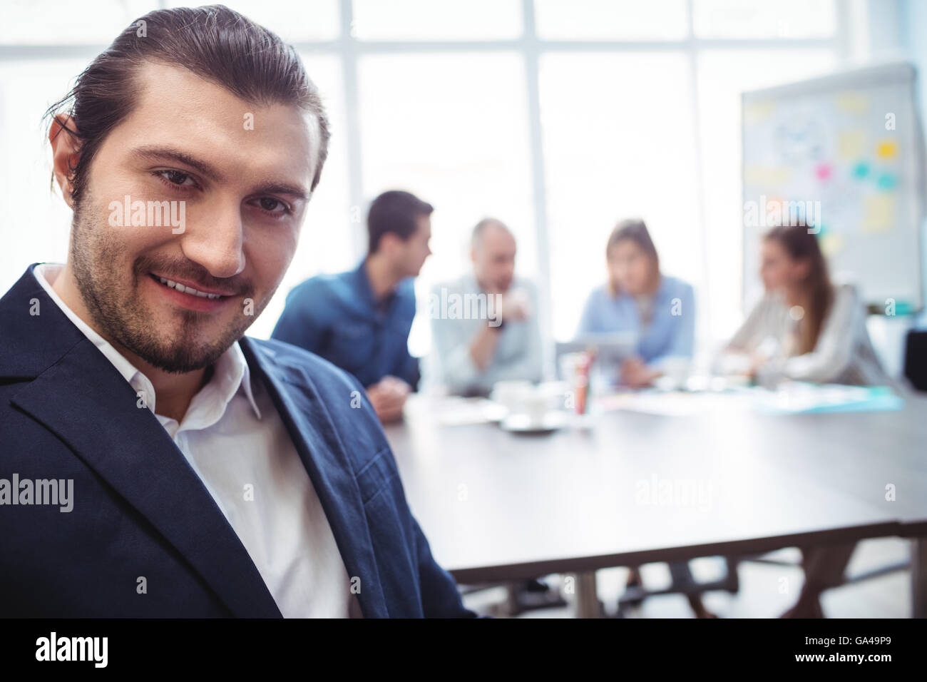 Ritratto di imprenditore sorridente contro i colleghi Foto Stock