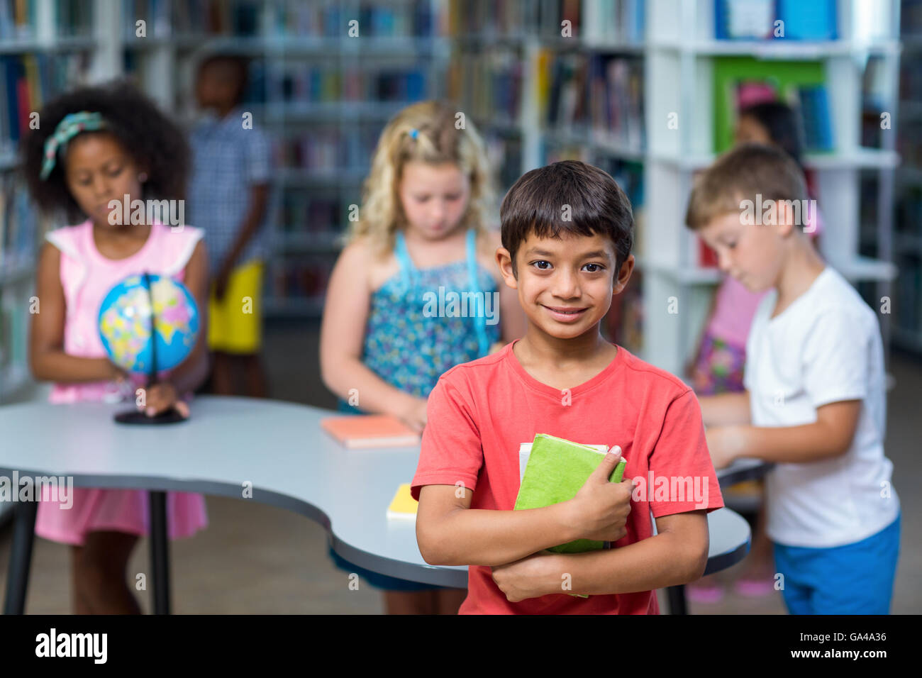 Ragazzo con libri contro i compagni di scuola Foto Stock