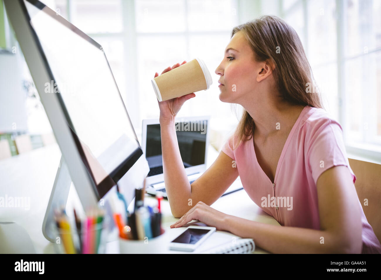 Graphic Designer di bere il caffè al banco Foto Stock