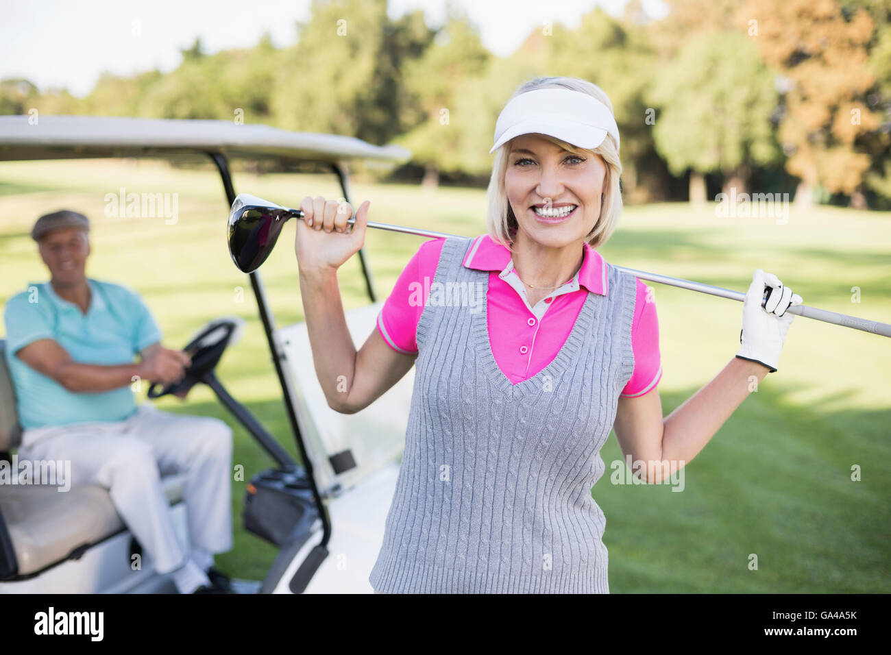 Felice donna matura portante golf club mentre in piedi da uomo Foto Stock