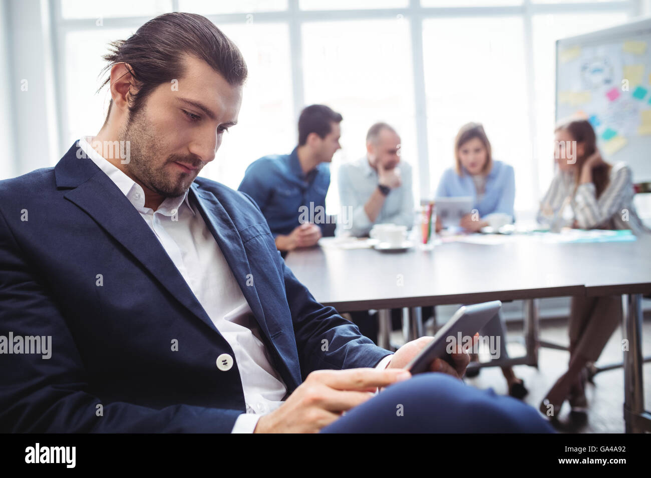 Fiducioso imprenditore utilizzando digitale compressa contro i colleghi Foto Stock