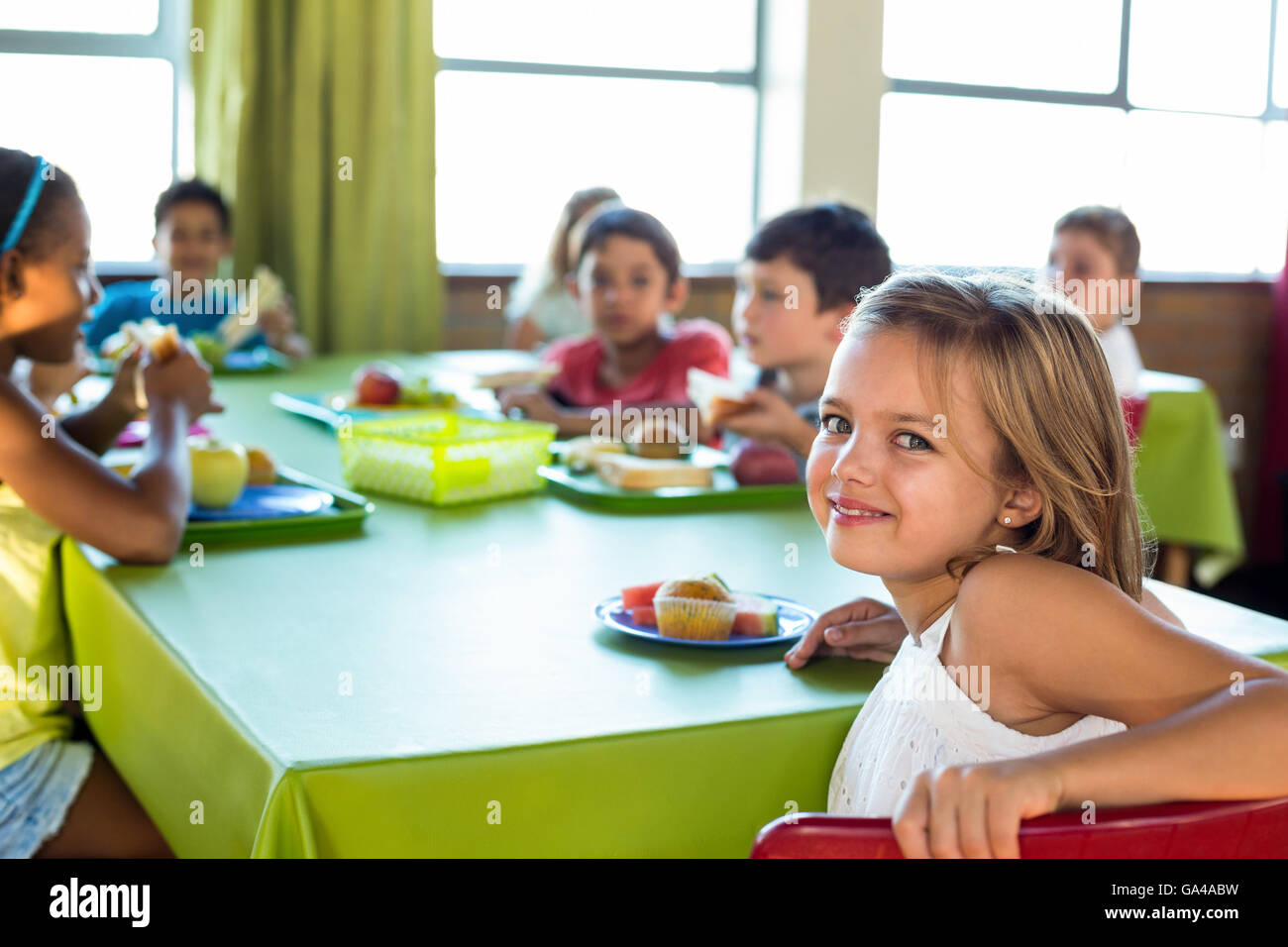 Ragazza carina con i compagni di classe avendo pranzo Foto Stock