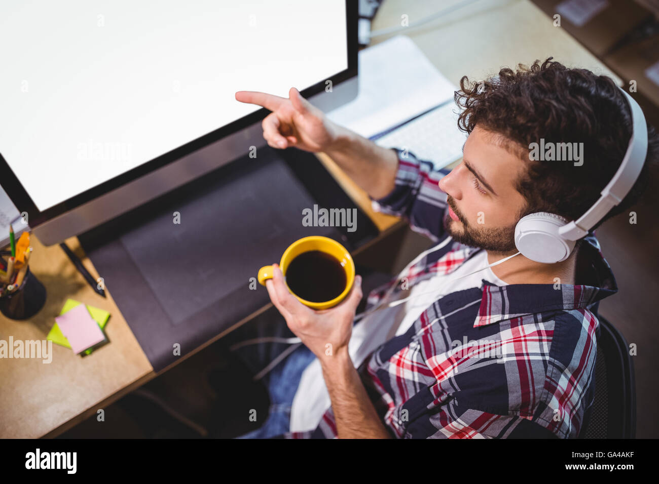 Imprenditore puntando al monitor del computer mentre si beve il caffè Foto Stock