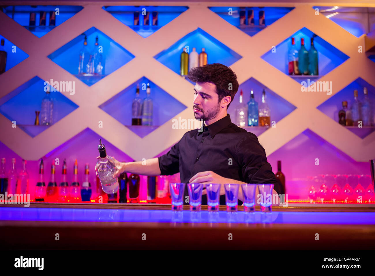 Barista versando alcool nel colpo di vetro al bancone Foto Stock