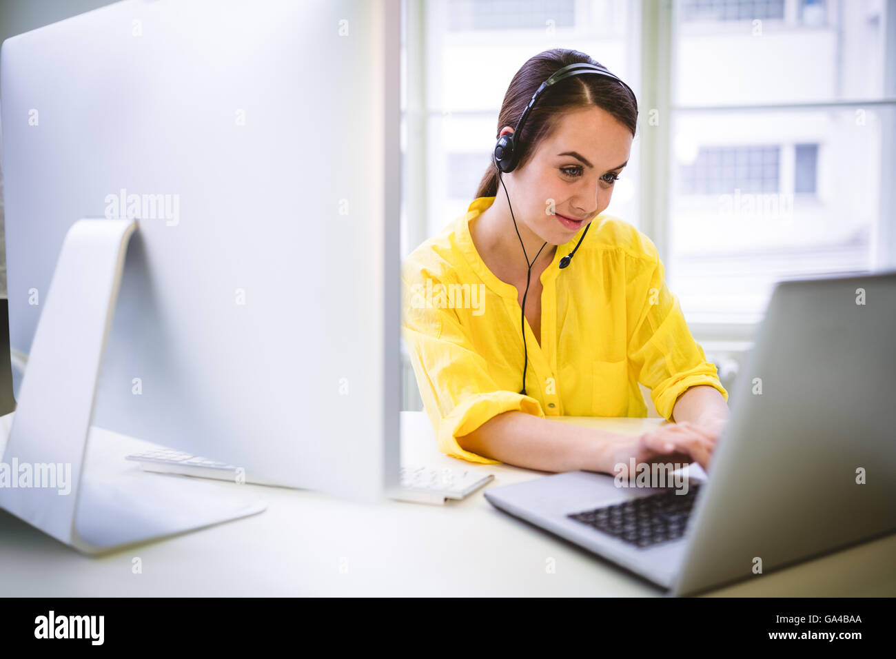 Operatore felice multi-tasking presso il creative office Foto Stock
