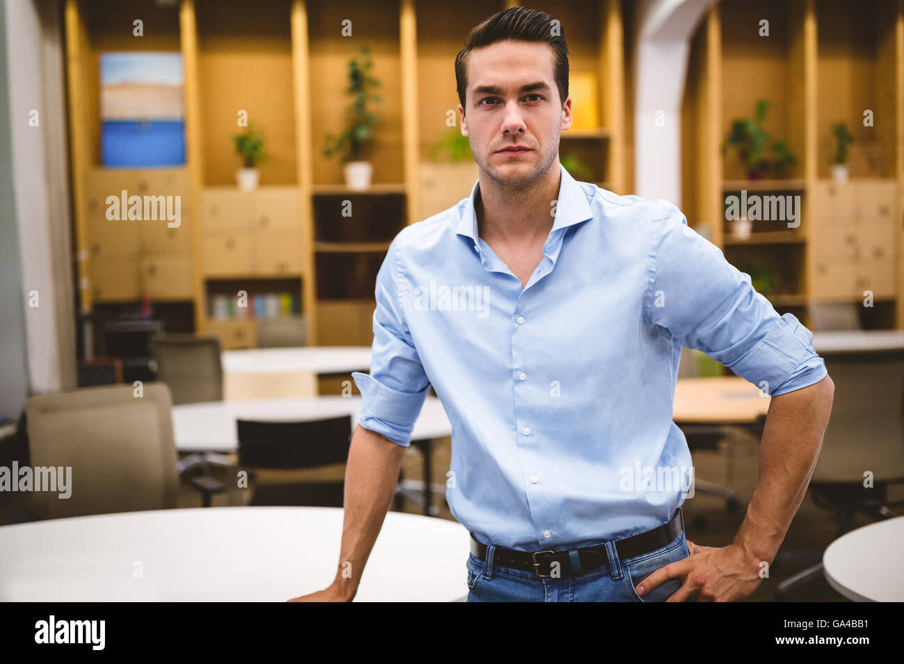 Fiducioso imprenditore con mano su anca in sala riunioni Foto Stock