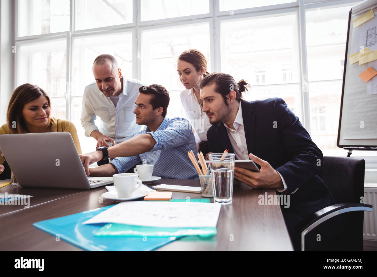 Imprenditore spiegare ai colleghi con il computer portatile nella sala riunioni Foto Stock