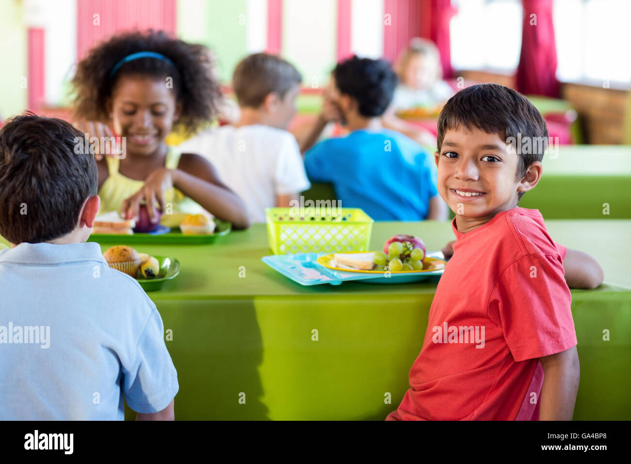 Ragazzo con i compagni di scuola avendo pranzo Foto Stock