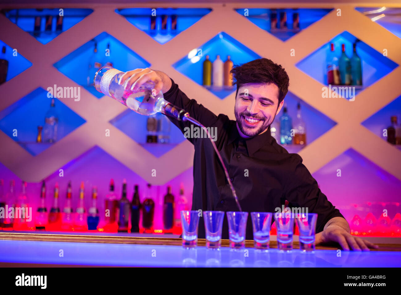 Barman sorridenti mentre la colata di alcool nel colpo di vetro Foto Stock