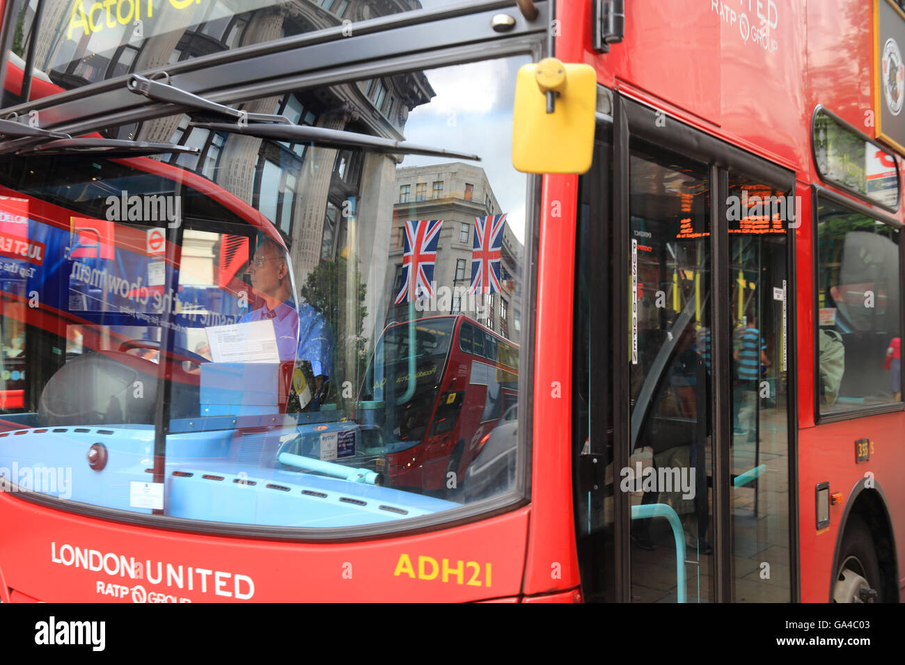 Union Jack Flag si riflette in un rosso London bus della finestra nel West End, su Oxford Street, in Inghilterra, Regno Unito Foto Stock