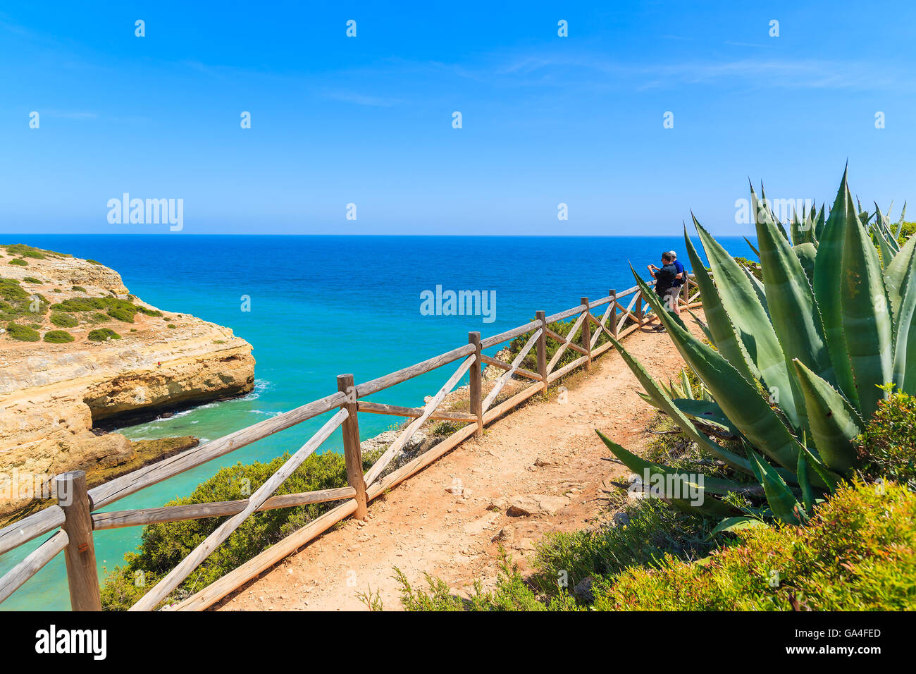 I turisti sulla scogliera percorso lungo mare guardando bella baia mare vicino alla città di Carvoeiro, Portogallo Foto Stock