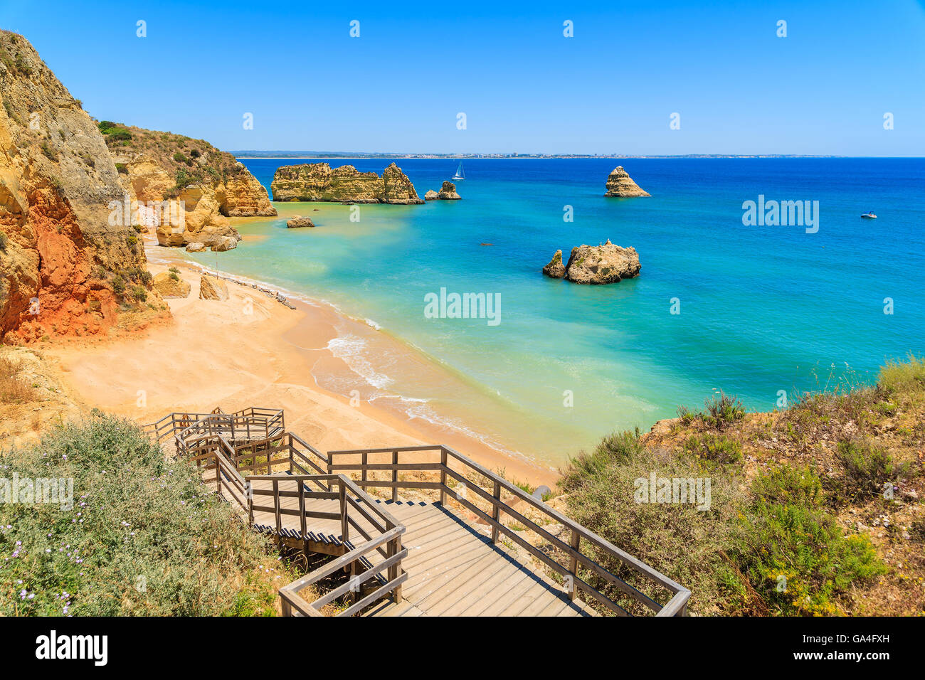 Passerella in legno per la famosa Praia Dona Ana beach con acqua del mare turchese e scogliere, Portogallo Foto Stock