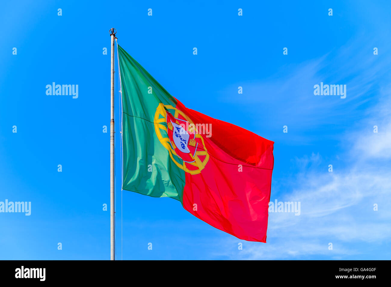 Bandiera portoghese sventolare nel vento contro un cielo blu sullo sfondo a Silves castello, Portogallo Foto Stock