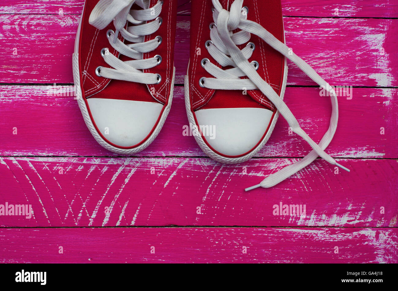 Coppia di red sneakers con lacci bianco rosa su sfondo di legno Foto Stock
