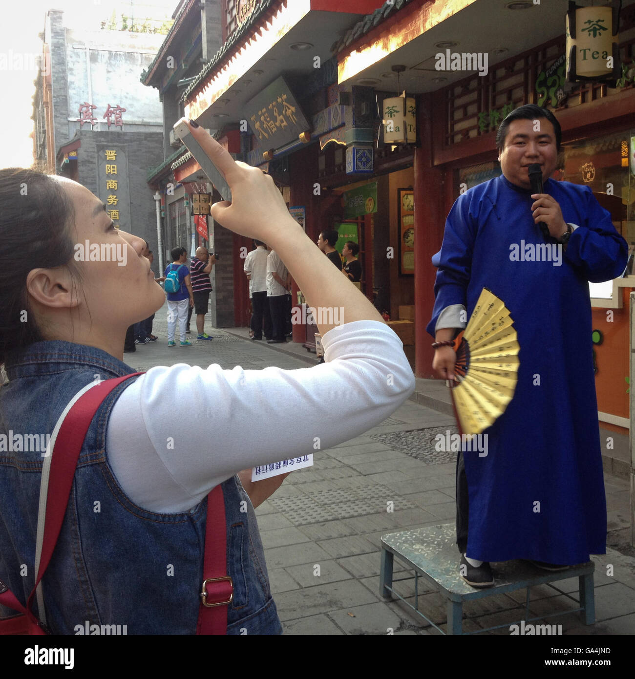 Donna di fotografare e un commesso al di fuori del negozio, Dashilar Hutong distretto, a Pechino, in Cina. Foto Stock