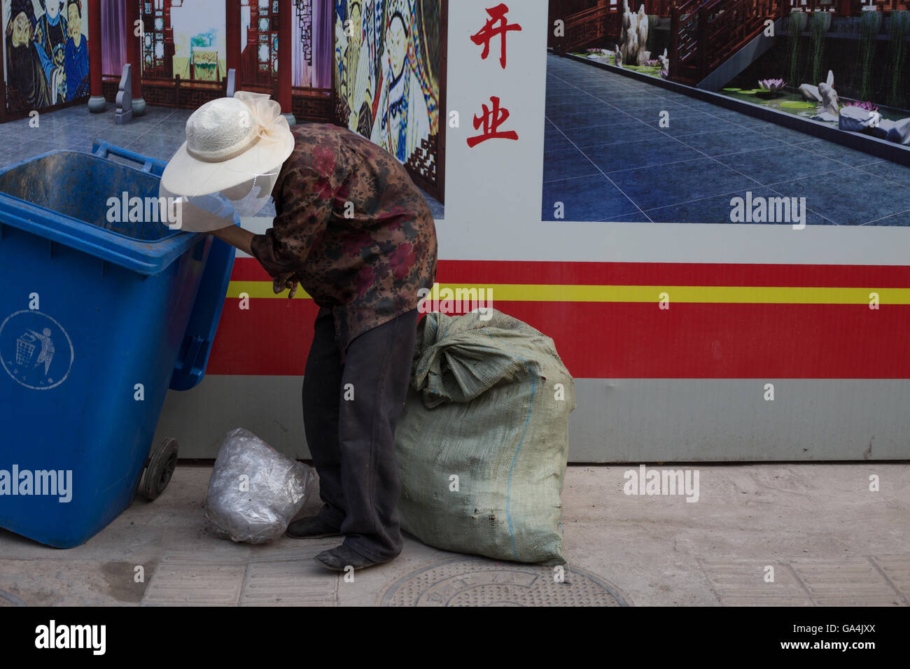 Vecchia donna controllare gli scomparti per le cose a rivendere in Shitou e Dashilar hutong area, a Pechino, in Cina. Foto Stock