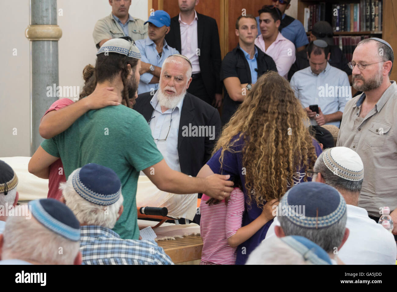 Israele. 3 Luglio, 2016. Il rabbino Benjamin Klemanson, testa del religioso ebraico shcool ("Yeshiva') in Otniel, comfort alcuni figli di Michael Mark, un padre di dieci uccisi dai terroristi palestinesi che ha girato a sua auto (la moglie e due dei suoi figli sono stati gravemente feriti) come il loro approccio il scialle-corpo coperto di loro padre. Credito: Yagil Henkin/Alamy Live News Foto Stock