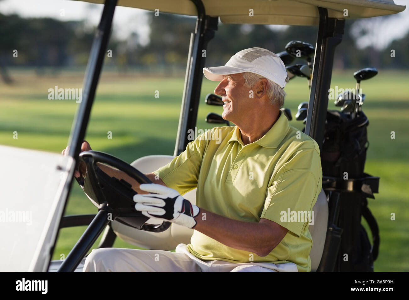 Sorridente uomo maturo la guida golf buggy Foto Stock