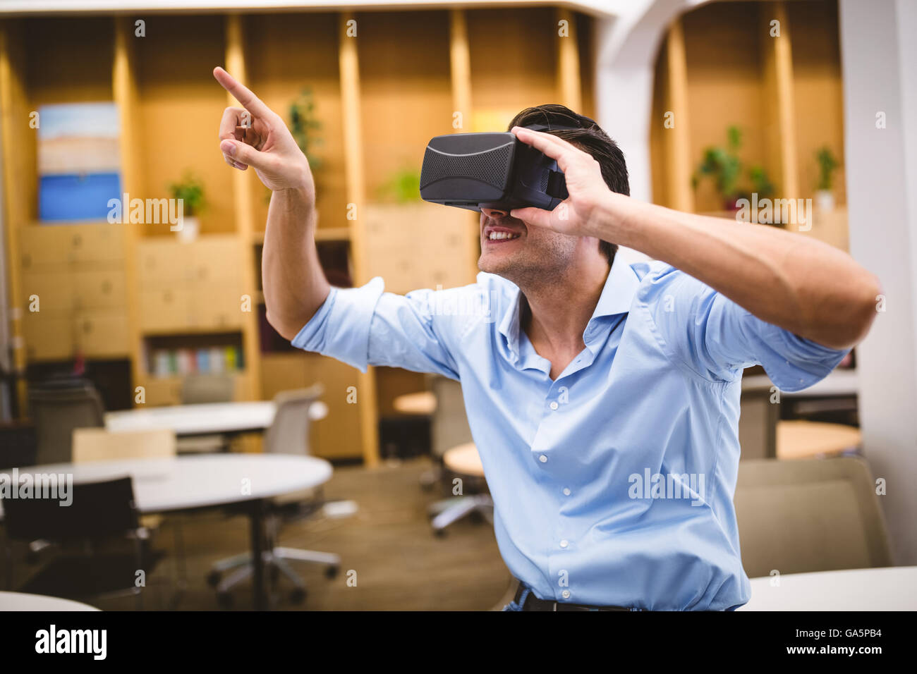 Giovane dirigente godendo la realtà aumentata auricolare in ufficio Foto Stock