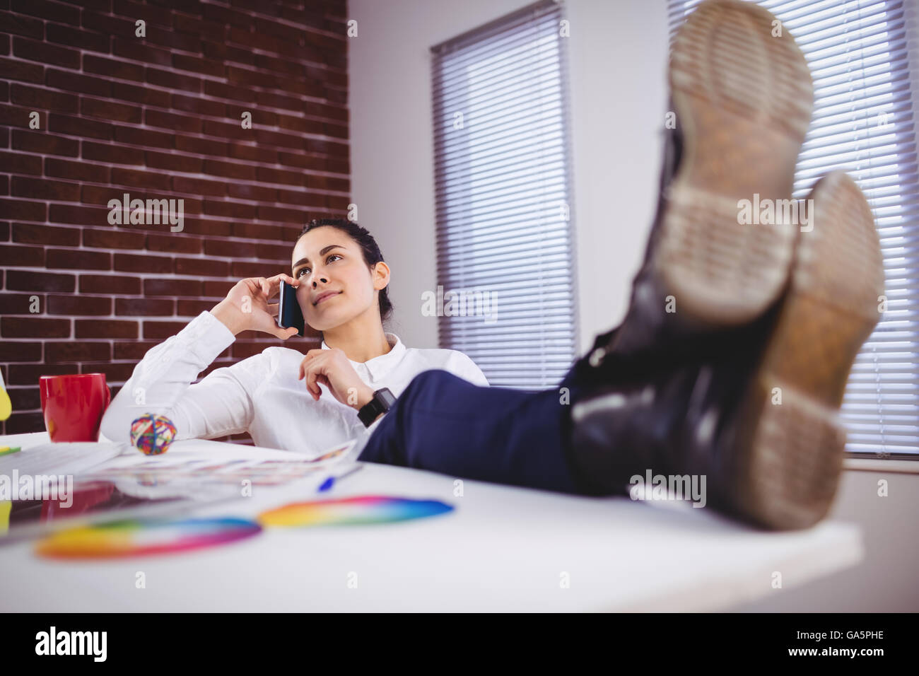 Giovane donna parlando al telefono in ufficio Foto Stock