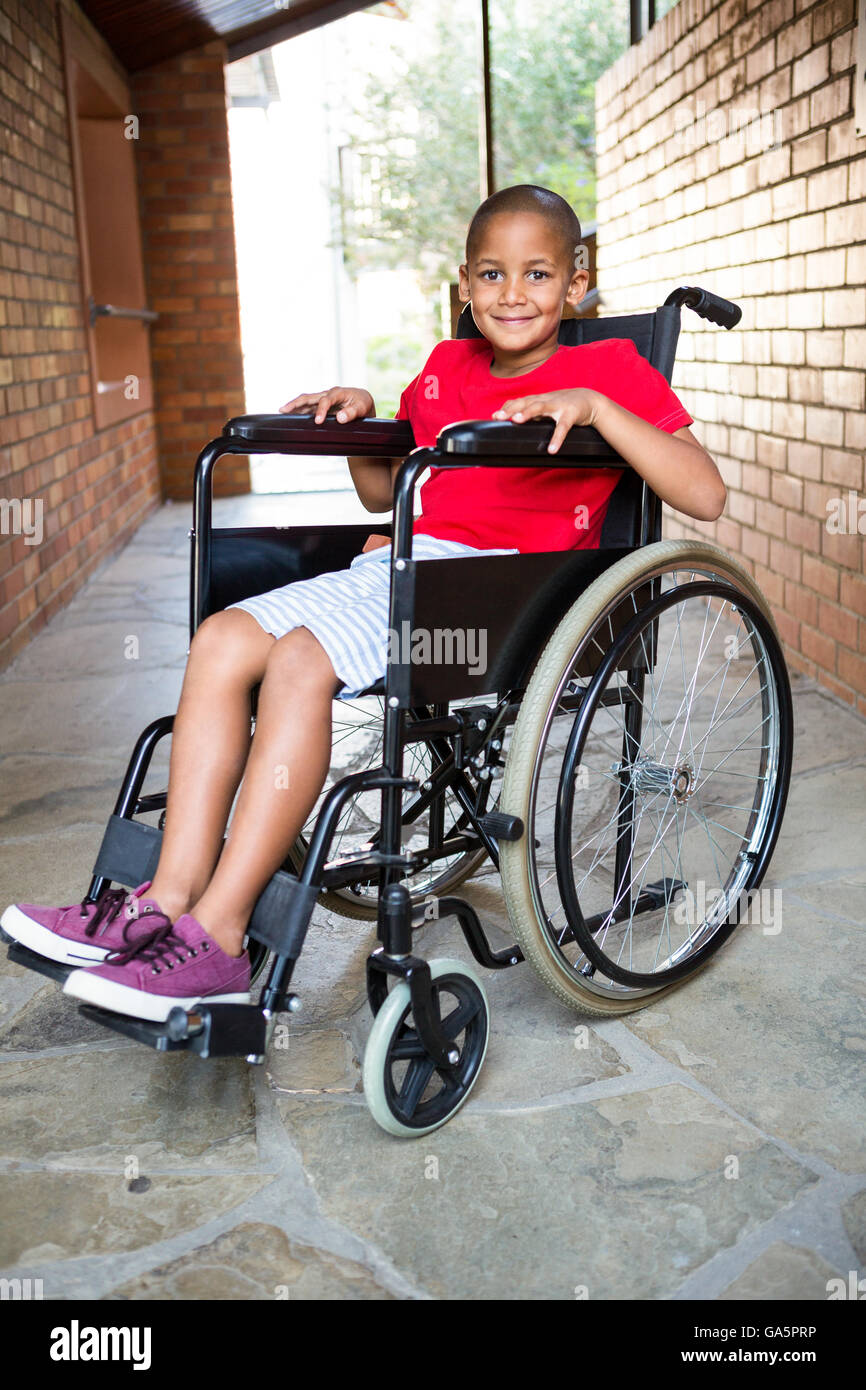 Sorridente ragazzo disabile a scuola corridoio Foto Stock