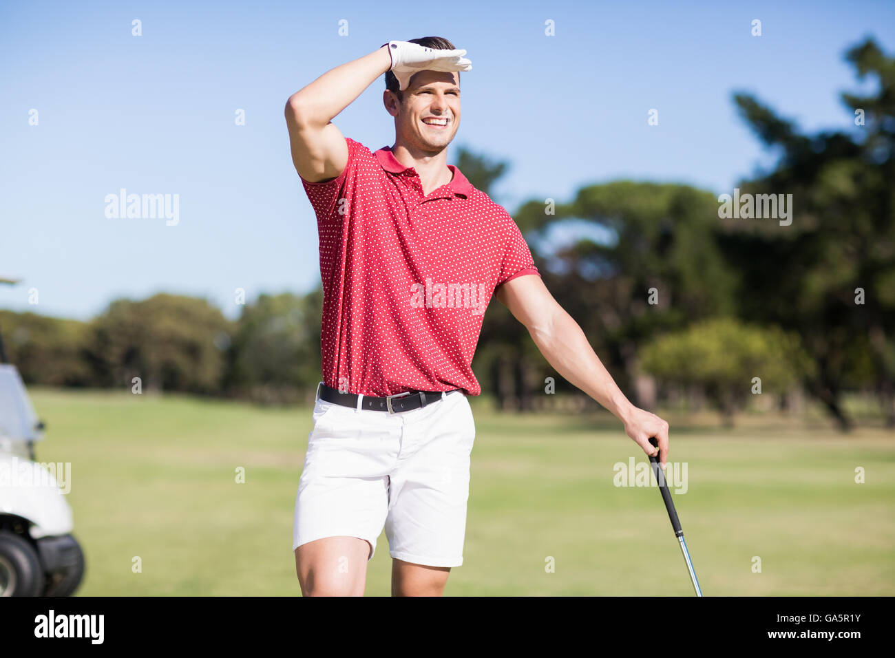 Sorridente golfista occhi di schermatura Foto Stock