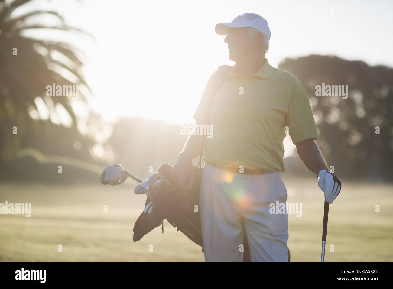 Uomo maturo che trasportano borsa da golf mentre si sta in piedi sul campo Foto Stock