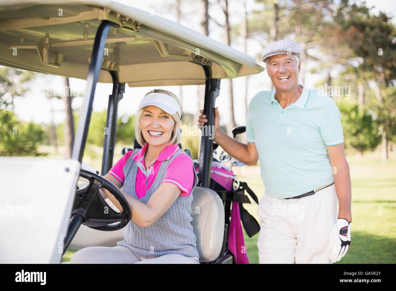 Sorridente Coppia matura con donna seduta in golf buggy Foto Stock